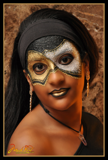 woman weaing a painted on mask that has a ying and yang feel in gold and silver
